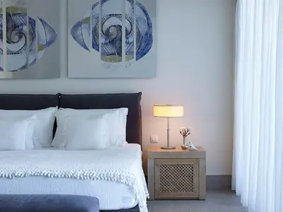a bedroom with a bed and a table with a lamp at Aquagrand Artistic Luxury Beach Resort - Adults Only in Líndos
