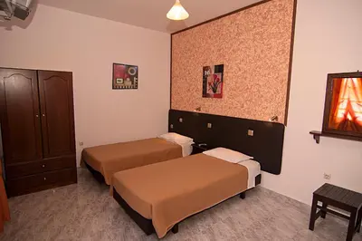 a hotel room with two beds and a cabinet at Lindos Panorama in Líndos