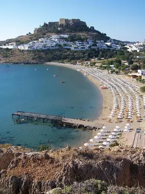 a beach with a bunch of umbrellas and a pier at Lindos Panorama in Líndos