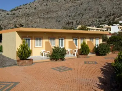 a yellow building with chairs and tables in front of it at George Studios Pefkos in Pefki Rhodes