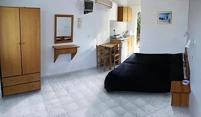 a bedroom with a black bed and a kitchen at George Studios Pefkos in Pefki Rhodes
