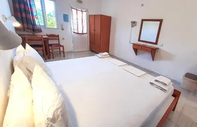 a bedroom with a large white bed and a mirror at George Studios Pefkos in Pefki Rhodes
