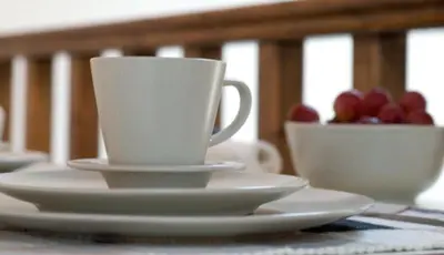 two cups and plates on a table with a bowl of fruit at Domus Studios in Rhodes Town