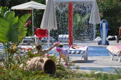 a little girl laying on a chair in front of a fountain at Matina Pefkos Aparthotel in Pefki Rhodes