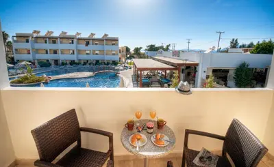 a balcony with a table and chairs and a swimming pool at Matina Pefkos Aparthotel in Pefki Rhodes