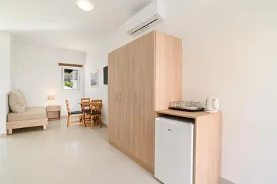 a kitchen with a wooden cabinet next to a living room at Matina Pefkos Aparthotel in Pefki Rhodes