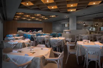 a dining room with white tables and chairs at Porto Angeli in Archangelos