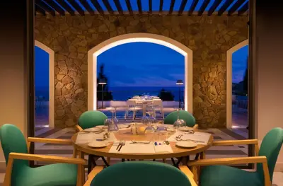 a dining room with a table and green chairs at Porto Angeli in Archangelos