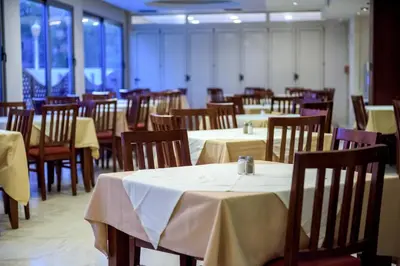 a dining room with tables and chairs with white table cloth at Manousos City Hotel in Rhodes Town