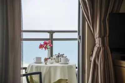 a table with cups and a vase of flowers on it at Manousos City Hotel in Rhodes Town