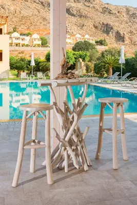 a table and two stools in front of a pool at Celestial Lindos Suites in Líndos