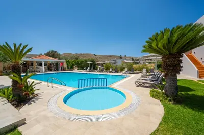a swimming pool with palm trees in a yard at Celestial Lindos Suites in Líndos