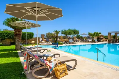 a pool with tables and umbrellas in front of a resort at Celestial Lindos Suites in Líndos