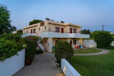 a large house with a white wall and bushes at Angela Studios Pefkos in Pefki Rhodes