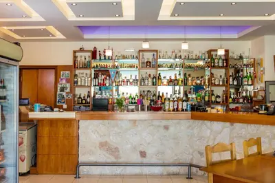 a bar in a restaurant with a lot of bottles at Ilyssion Holidays Hotel in Ialyssos