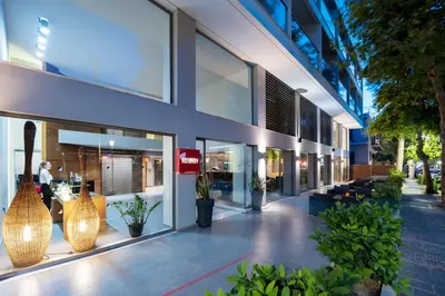 a large building with large glass windows and plants at Oktober Downtown Boutique Hotel in Rhodes Town