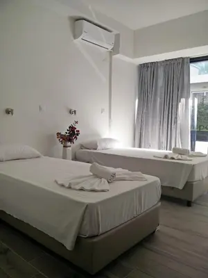 a white bedroom with two beds and a window at New York Hotel in Rhodes Town