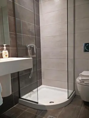 a shower with a glass door next to a toilet at New York Hotel in Rhodes Town