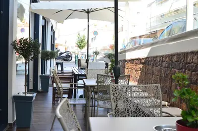 a restaurant with tables and chairs and an umbrella at New York Hotel in Rhodes Town