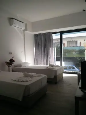 a hotel room with two beds and a large window at New York Hotel in Rhodes Town