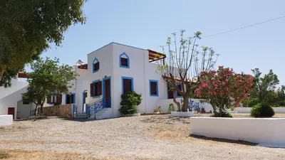a white house with blue windows and a tree at Andreas Studios in Pefki Rhodes