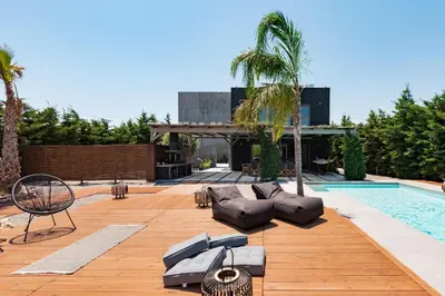 a pool with chaise lounges next to a house at Villa Eleven in Ialyssos