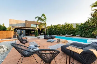 a patio with chairs and a couch and a pool at Villa Eleven in Ialyssos