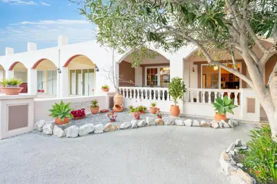 a house with a lot of potted plants in front of it at COLONIAL FAMILY apartment #4 ground floor in Faliraki