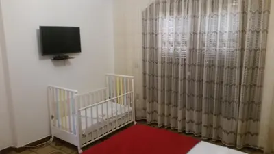 a room with a crib and a tv and curtains at Villa Agia Galini in Archangelos