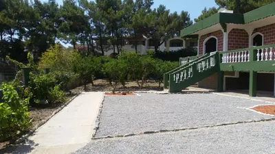 a walkway leading to a house with a green porch at Villa Agia Galini in Archangelos