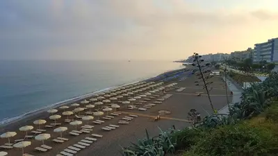 a beach with many umbrellas and the ocean at Suite Grand Maitre Rodos in Rhodes Town
