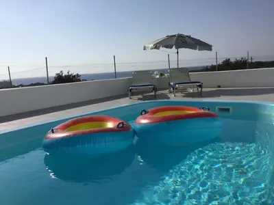 a swimming pool with two inflatable chairs and an umbrella at Sea Breeze Villas in Lachania