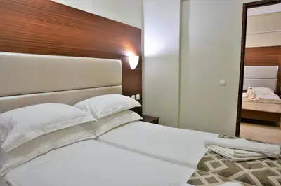 a bedroom with a white bed with a wooden headboard at Marathon Hotel - All Inclusive in Kolimbia