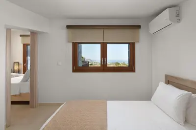 a white room with a bed and a window at Sperveri Enalio Villas - Heated Pool in Kolimbia