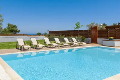 a swimming pool with a bunch of chairs around it at Sperveri Enalio Villas - Heated Pool in Kolimbia