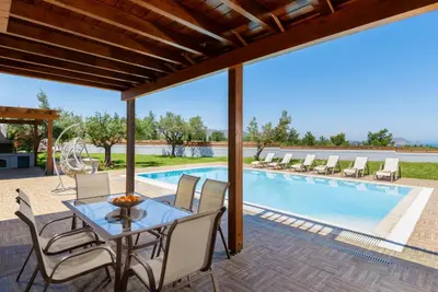 a patio with a table and chairs next to a swimming pool at Sperveri Enalio Villas - Heated Pool in Kolimbia