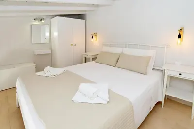 a white bedroom with a bed and a desk at Spitakia in Halki