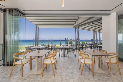 a restaurant with tables and chairs and a view of the ocean at Sun Beach Resort in Ialyssos