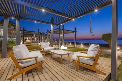 a wooden deck with chairs and a table and the ocean at Sun Beach Resort in Ialyssos
