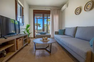 a living room with a couch and a tv and a table at Villa Sunrise by the Sea in Kiotari