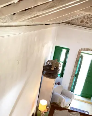 a living room with green windows and a table at Hypate, traditional island cottage in Halki
