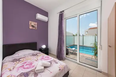 a bedroom with a bed and a balcony with a pool at Kiriakos Apartment in Afantou