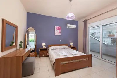 a bedroom with a bed and a vanity and a mirror at Kiriakos Apartment in Afantou
