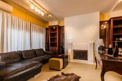 a living room with a leather couch and a fireplace at Lindos Villa Estelle in Líndos