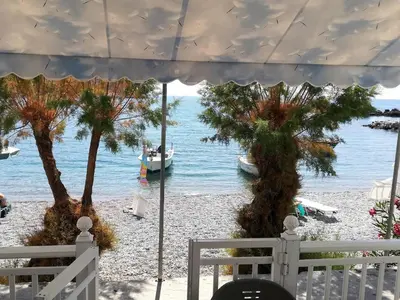 a view of the beach from a balcony with a boat in the water at Stamatia's House in Haraki