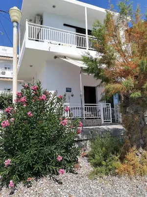 a white house with a balcony and pink flowers at Stamatia's House in Haraki