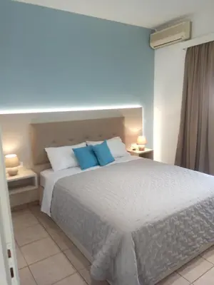 a bedroom with a large white bed with blue pillows at Stegna Bay Apartment in Archangelos