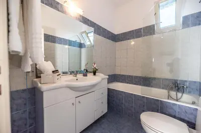 a bathroom with a sink and a tub and a toilet at Stegna Bay Apartment in Archangelos