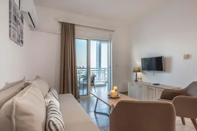 a living room with a couch and a table and a tv at Stegna Bay Apartment in Archangelos