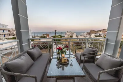 a balcony with two couches and a table with flowers at Stegna Bay Apartment in Archangelos